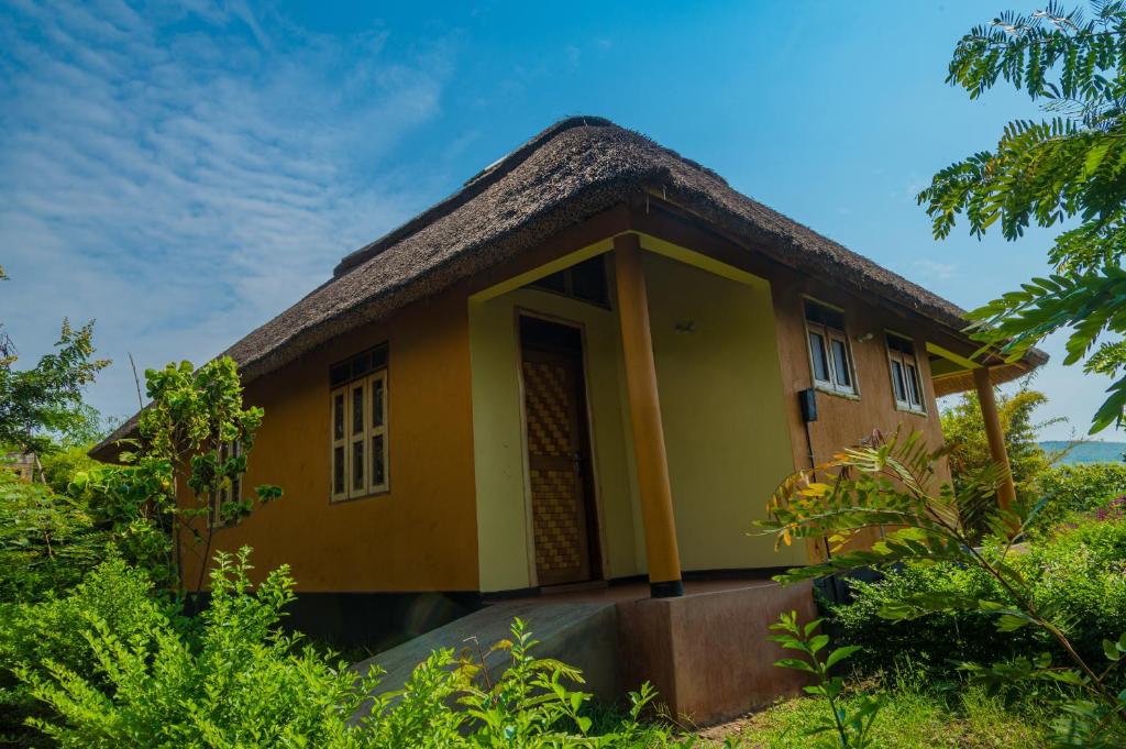 a small yellow house with a thatched roof at Nzoghu Heritage Safari Camp in Kasese