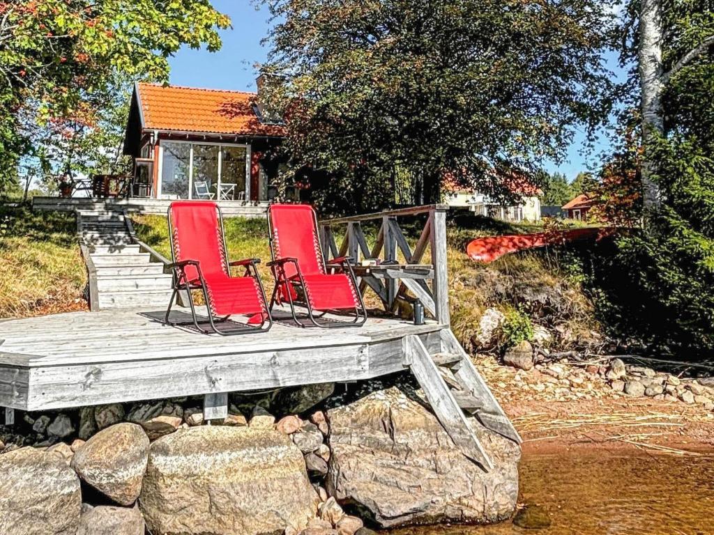 two red chairs sitting on a wooden deck at 2 person holiday home in Bellö-By Traum in Bellö