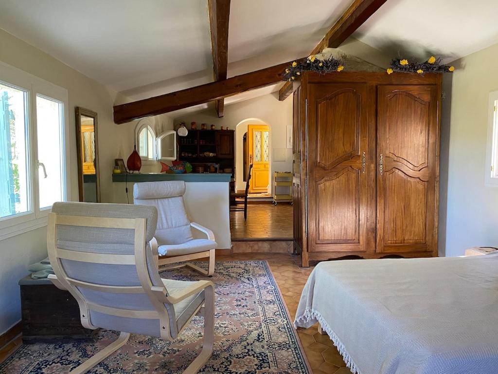 Un dormitorio con una cama y una silla dentro. en Bastidon, Petite bastide pour 2 avec bassin et jardin privé, en Crillon-le-Brave