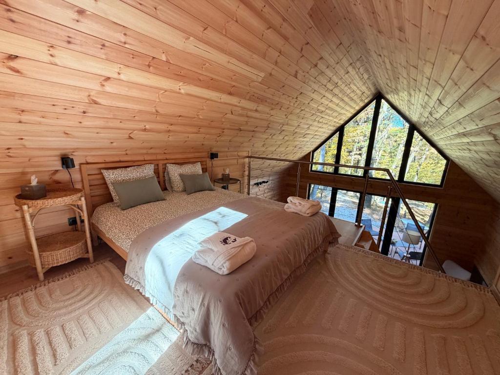 een slaapkamer met een bed in een houten hut bij Oaklounge Apartman in Kismaros