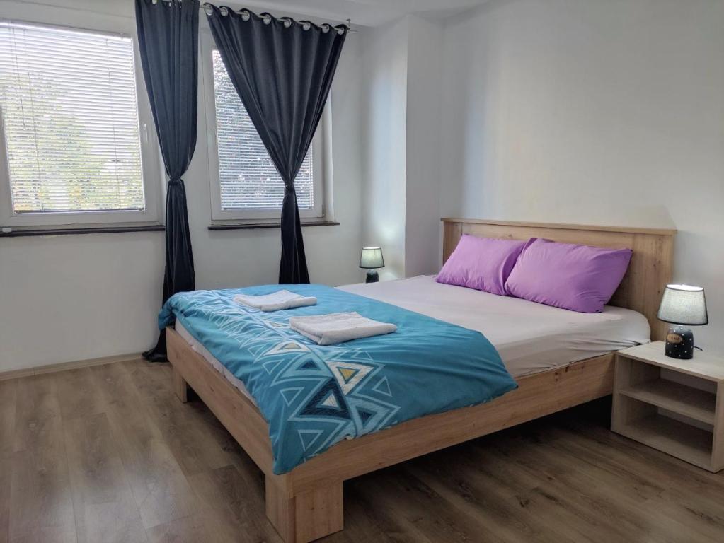 een slaapkamer met een groot bed met paarse en blauwe lakens bij Stefea Apartment in Ohrid