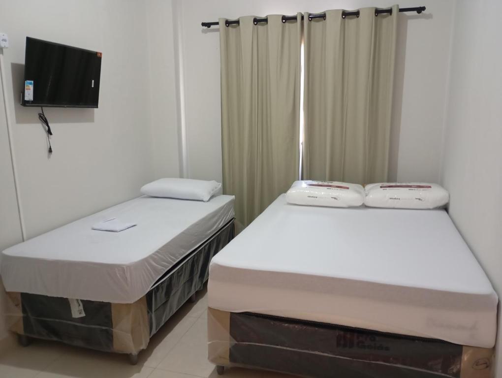 Cette chambre comprend 2 lits jumeaux et une télévision. dans l'établissement hotel pousada Maanaim, à Palmas