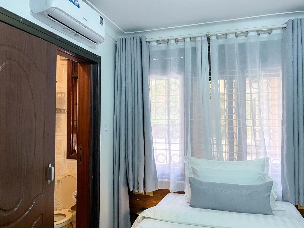 a bedroom with a bed with white sheets and a window at SKA The Boutique Naguru in Bukoto