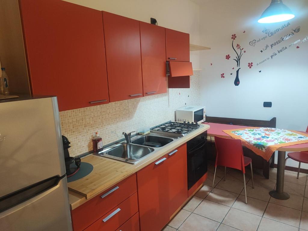 Leo House في تْريتسو سولاّدا: مطبخ مع دواليب حمراء ومغسلة وطاولة