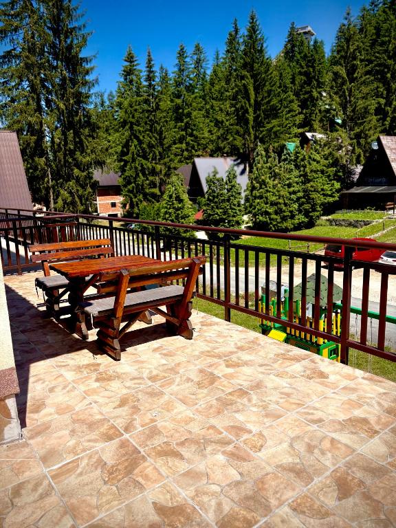 two wooden benches sitting on a patio next to a fence at Apartman RAJAN Vlašić in Vlasic