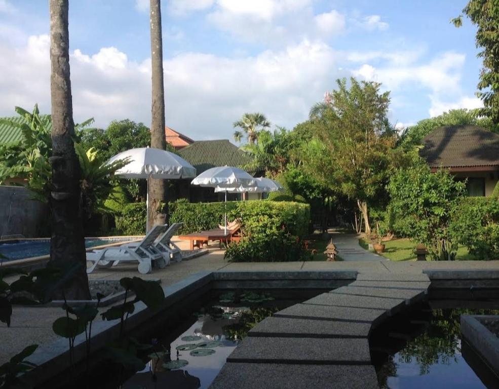ein Pool in einem Resort mit Sonnenschirmen in der Unterkunft Rawai Boutique Resort in Rawai Beach