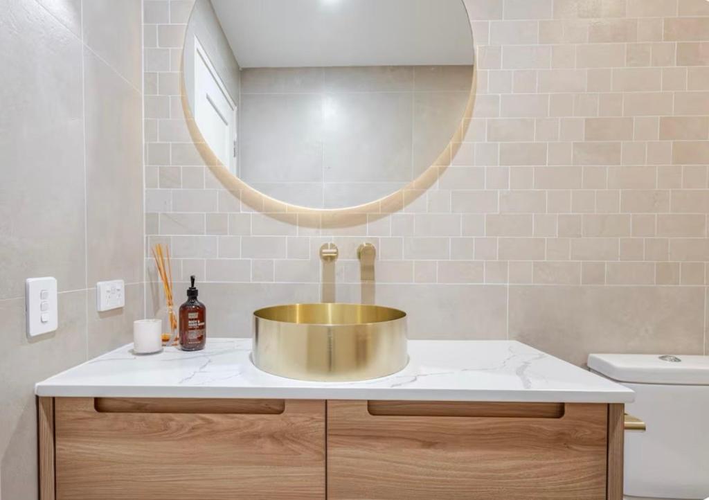 a bathroom with a gold sink and a mirror at Upscale neighbourhood guest quarters in Perth