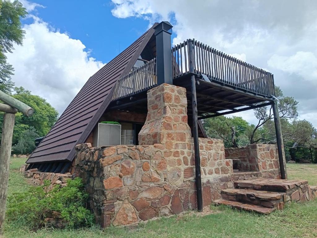 ein Steingebäude mit einer Terrasse darüber in der Unterkunft Cosy Cottage in Buffelspoort