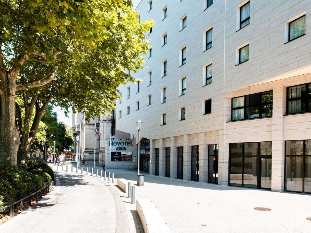 a building with a tree in front of it at Novotel Atria Nimes Centre in Nîmes