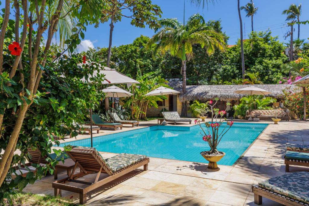 una piscina en un complejo con sillas y árboles en Controvento Boutique Hotel, en Cumbuco