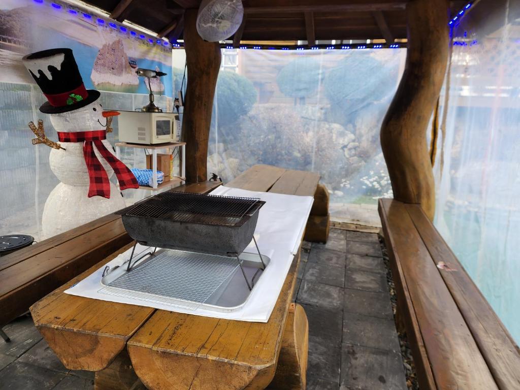 Una habitación con una mesa con parrilla y un muñeco de nieve. en 단양추억펜션, en Paegam