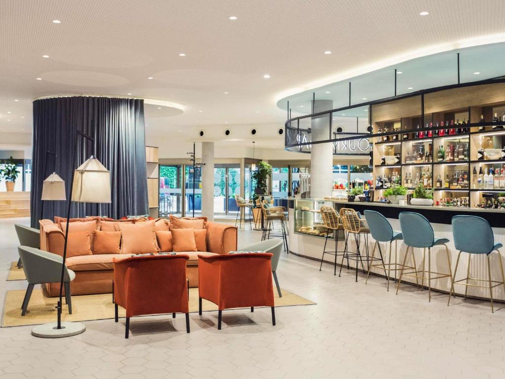 a lobby with a couch and chairs and a bar at Novotel Campo De Las Naciones in Madrid