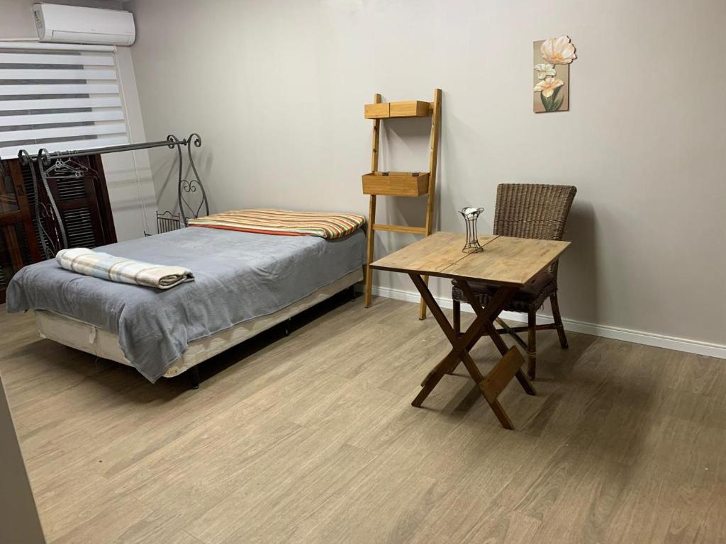 een slaapkamer met een bed, een bureau en een tafel bij House Bela Vista in Porto Alegre