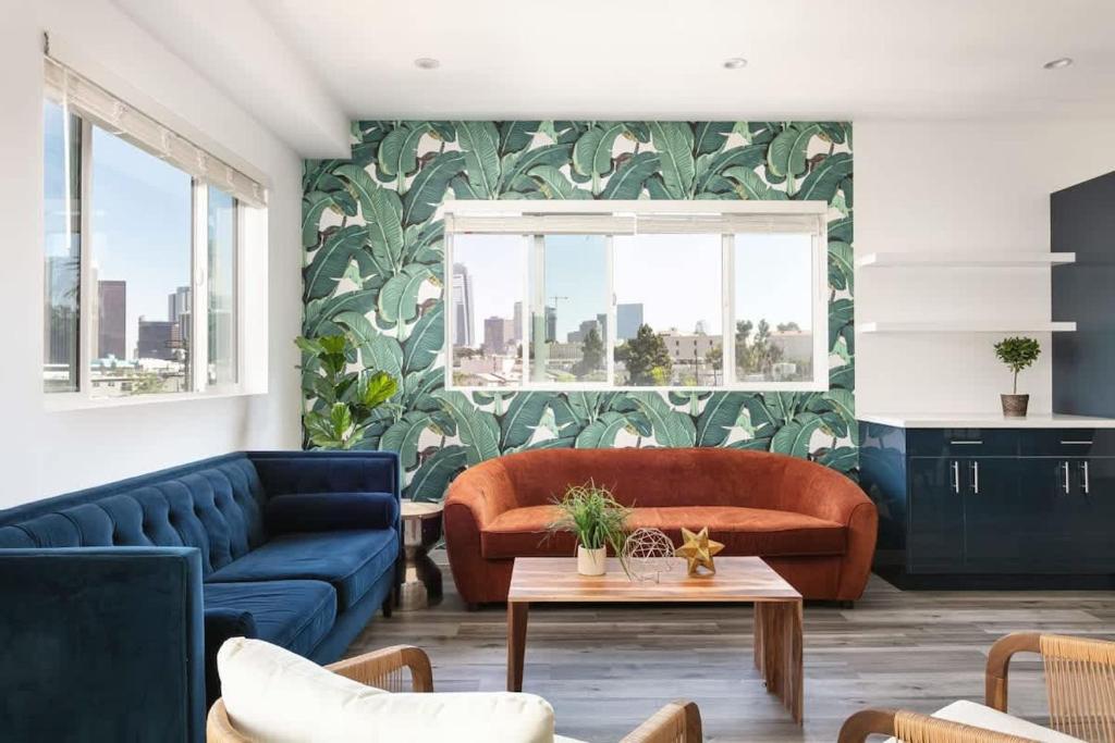 ein Wohnzimmer mit zwei blauen Sofas und einem Wandgemälde in der Unterkunft Prestige 5BR Townhome Near LA Hot Spots in Los Angeles