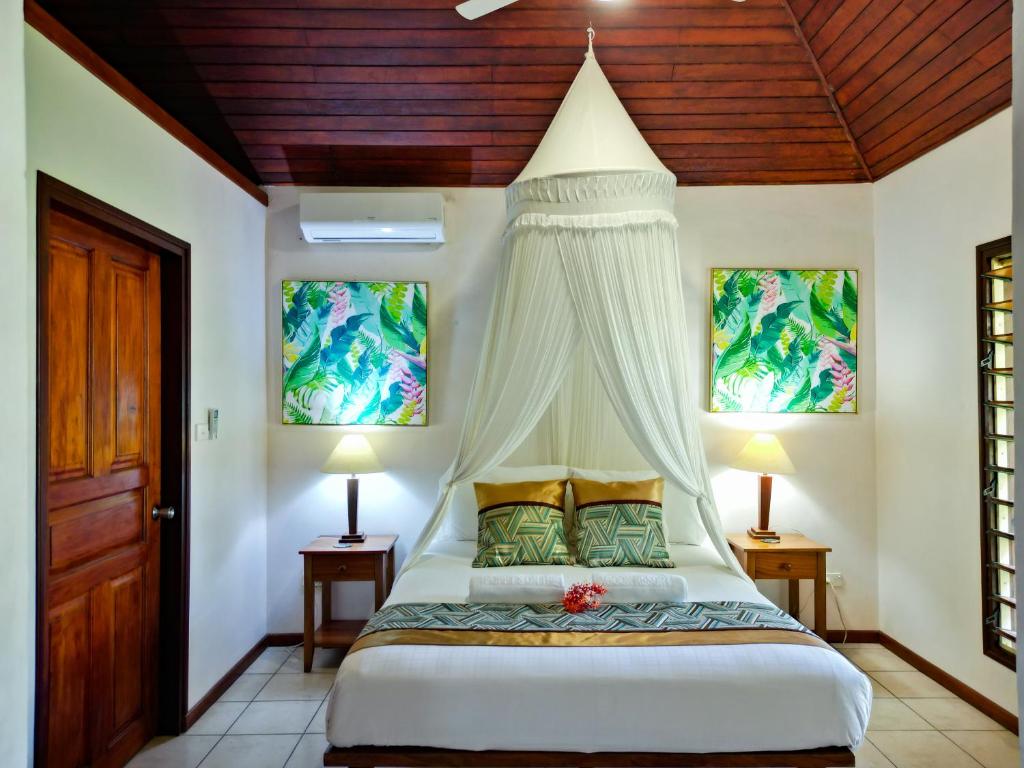 a bedroom with a bed with a canopy at Poppy's on the Lagoon in Port Vila