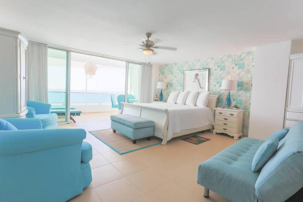 een slaapkamer met een bed en een bank en stoelen bij Luxury Penthhouse Frente Al Mar in Villas del Mar