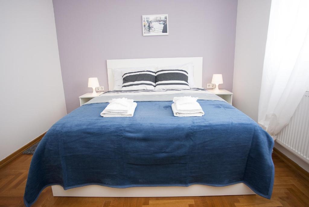 a bedroom with a large blue bed with two pillows at Paw Rooms in Zagreb