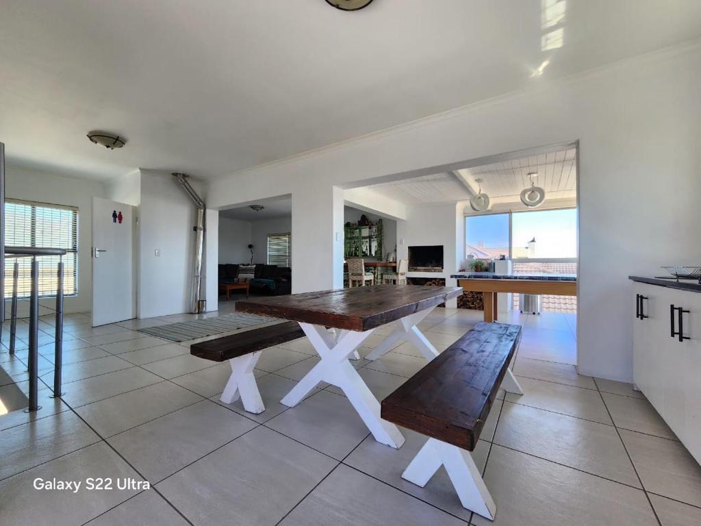 a dining room with a wooden table and benches at 87 on Sunbird in Langebaan