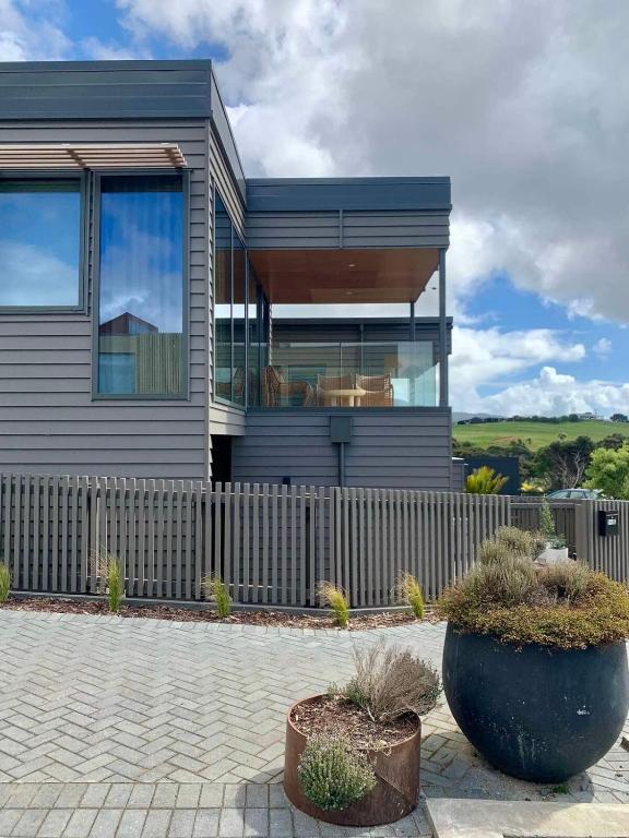 a house with a fence and two large windows at Tranquil 3 bedroom Retreat in Raglan in Raglan