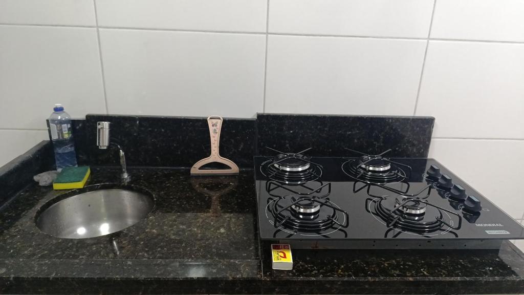 a kitchen counter with a stove and a sink at Alojamento in Caxias do Sul