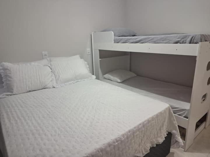 a bedroom with a bunk bed and a white bunk bedskirts at Ap 440 m do mar, próx Beto Carrero in Navegantes