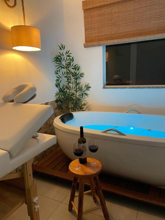 a bathroom with a tub and two glasses of wine at Quase um Spa in Petrópolis