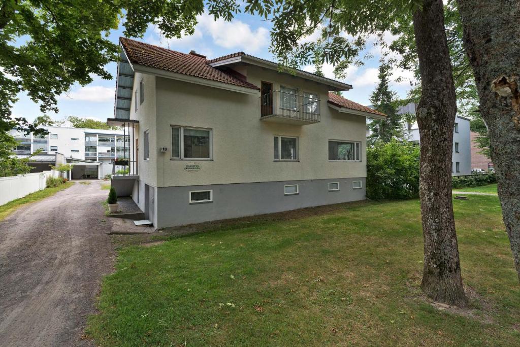 una casa con un árbol delante de ella en Majoitushuoneisto Tuomipuisto, en Naantali