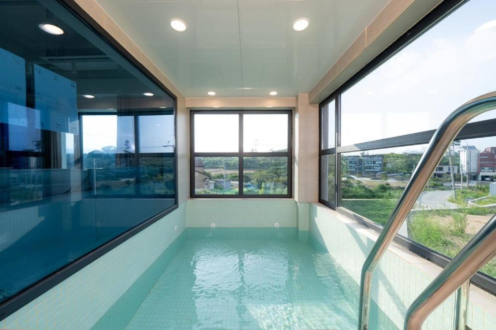 - une piscine dans un bâtiment avec fenêtres dans l'établissement Gangneung Stayharam Villa, à Kyŏngp'o-mal