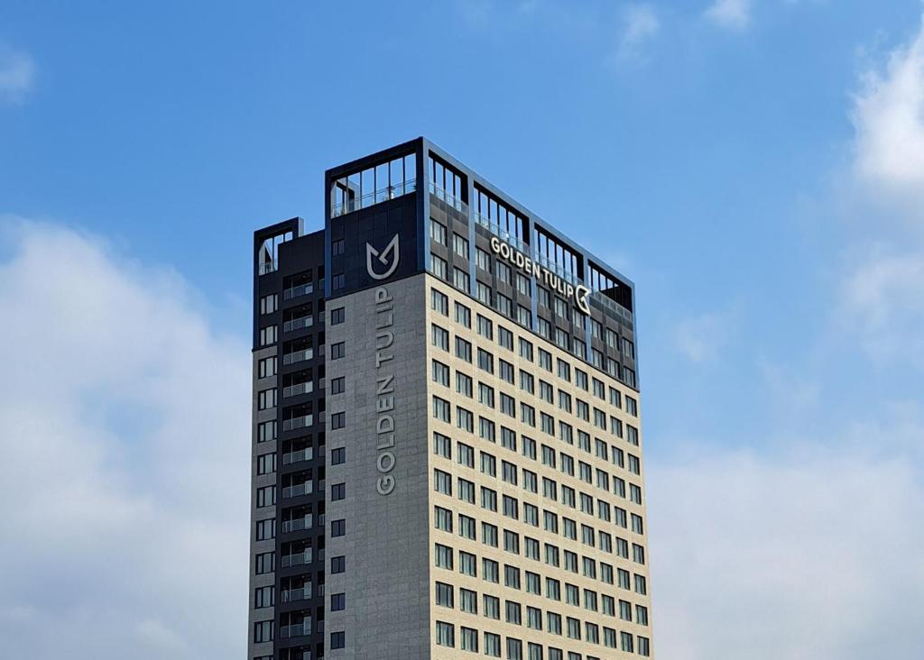 a tall building with a sign on the top of it at Golden Tulip Ever Yongin Hotel in Tugyeul