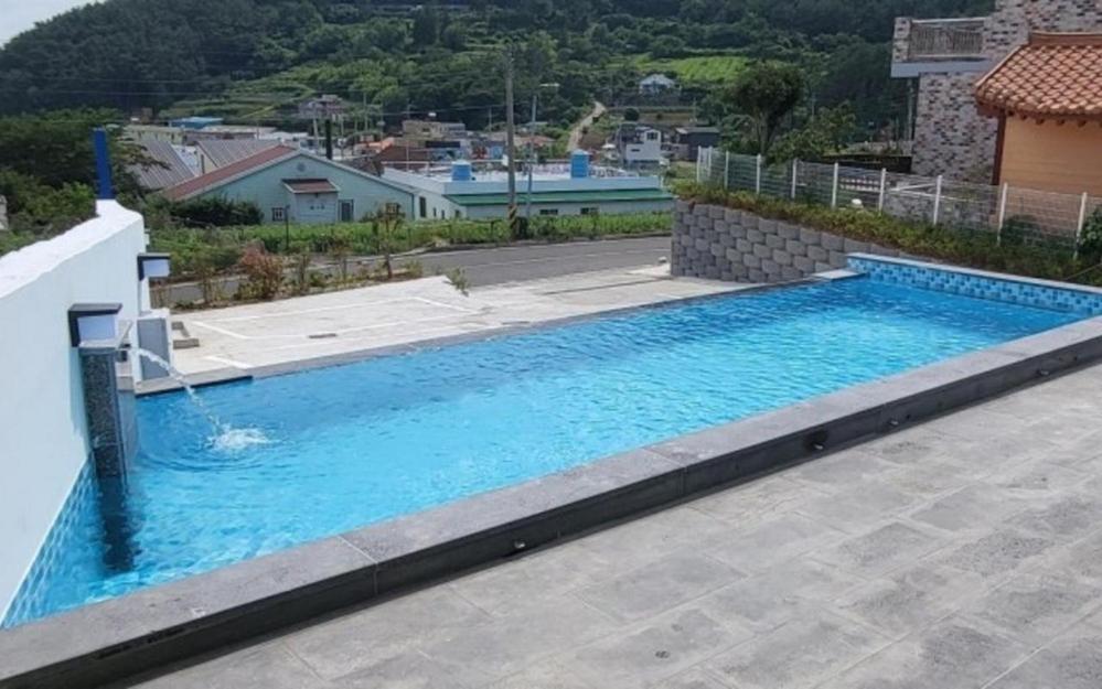 a large blue swimming pool on top of a house at Geoje View Pension in Geoje 