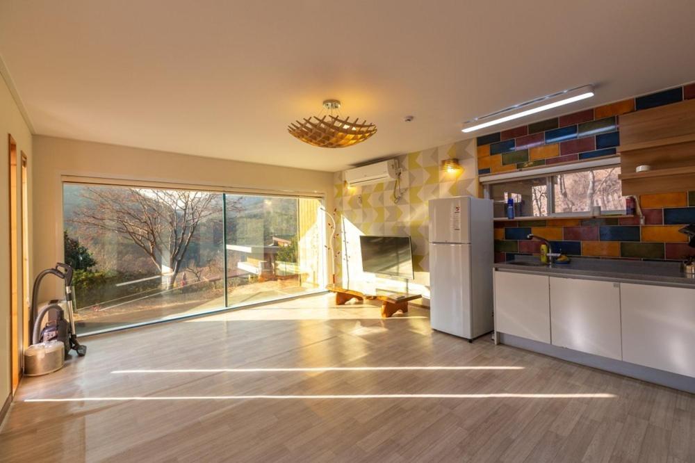 a kitchen with a refrigerator and a large window at Hwasun Byeolsan Pension in Wajun