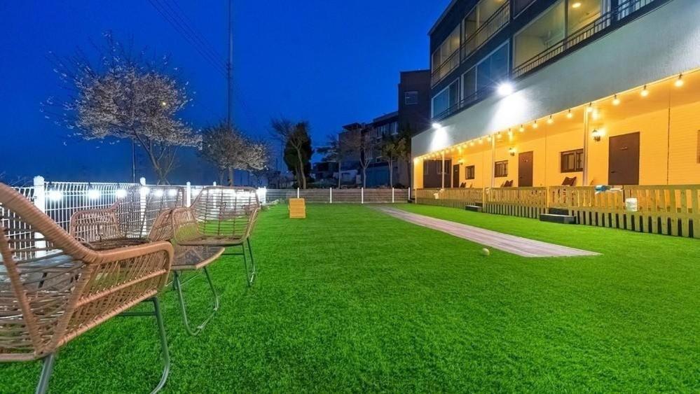 a row of chairs on a lawn in front of a building at Glamdog Dog Pension Yeongheungdo Branch in Pŏdŏni
