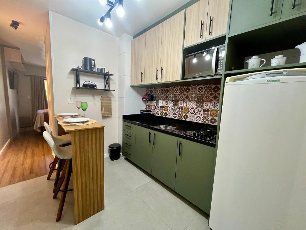 a kitchen with green cabinets and a table and a refrigerator at AP no centro com garagem in Caxias do Sul