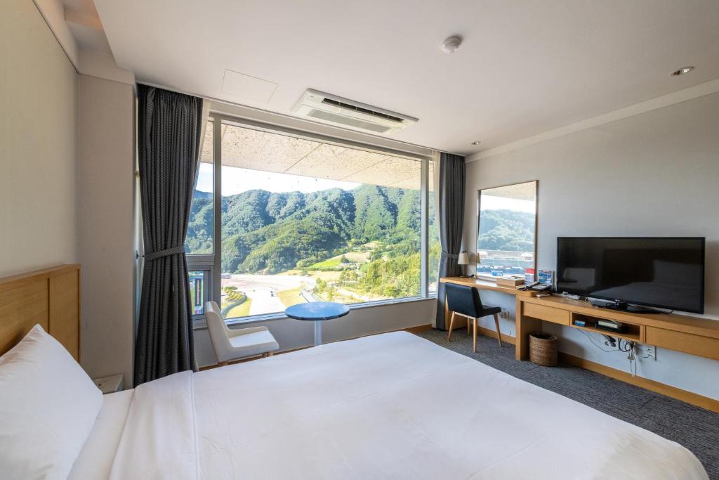 a hotel room with a bed and a desk and a television at Take Hotel & Resort Inje Speedium in Inje