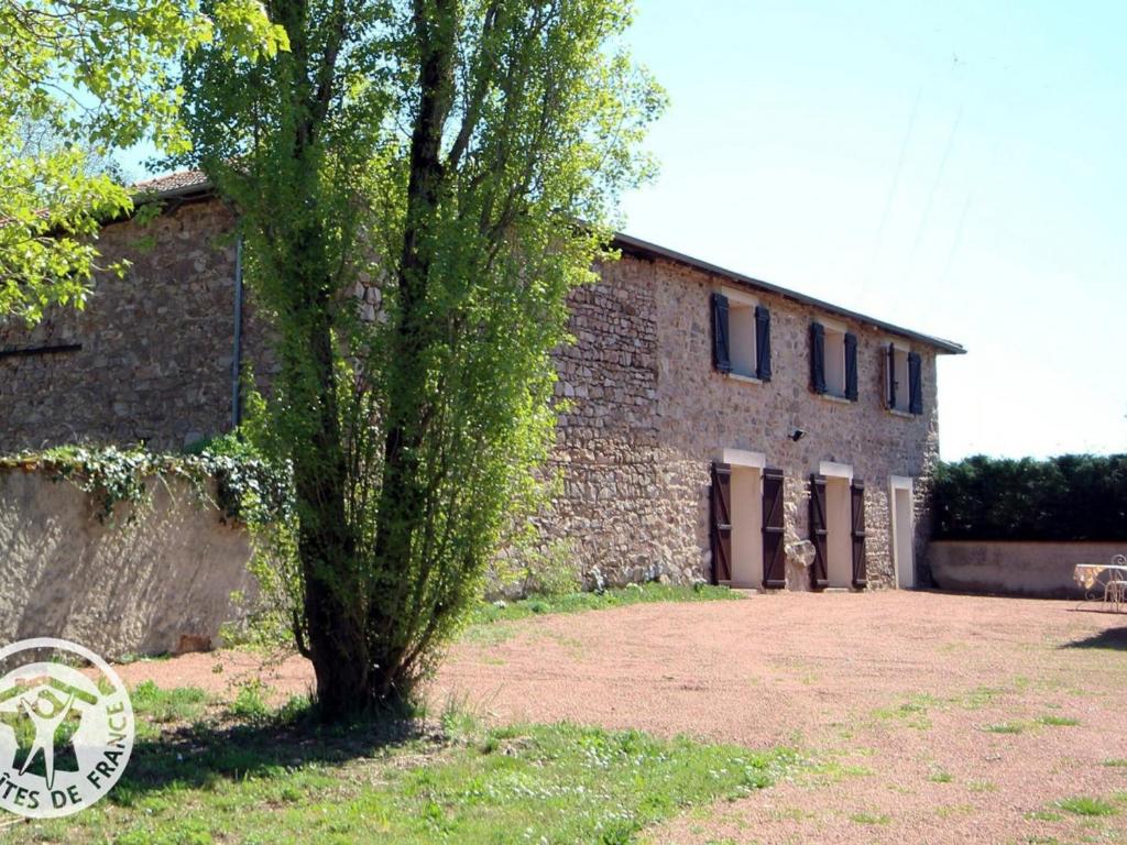 a tree in front of a brick building at Gîte spacieux avec piscine et animaux admis à St Haon le Vieux - FR-1-496-156 in Saint-Haon-le-Vieux