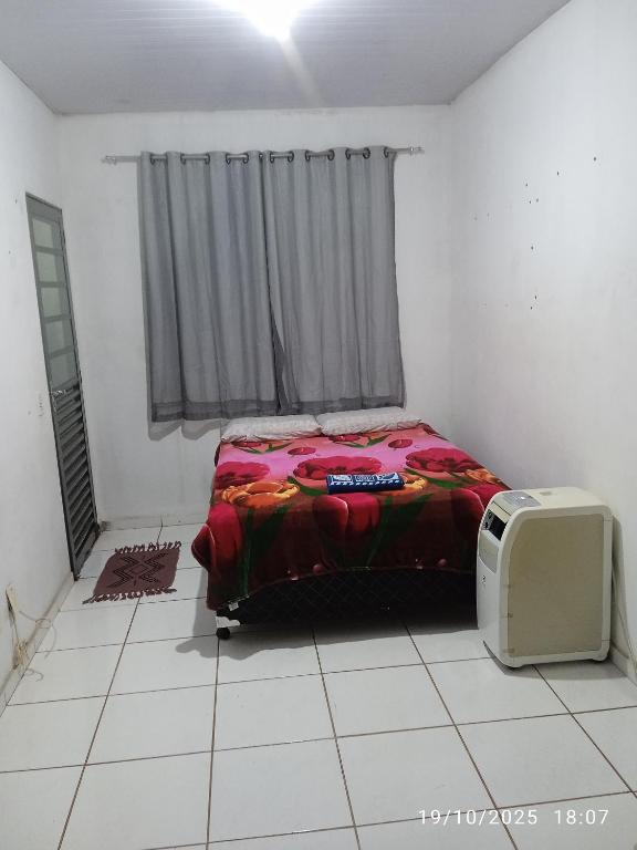 1 dormitorio con 1 cama y TV en el suelo en hospedagem Primavera, en Primavera do Leste