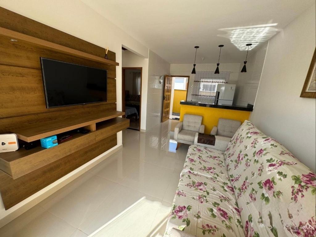 un salon avec un canapé et une télévision à écran plat dans l'établissement Casa de praia em Cabo Frio, à Cabo Frio