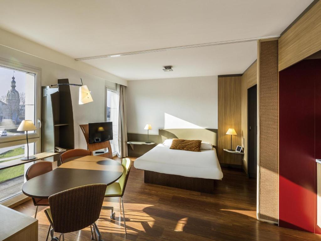 une chambre d'hôtel avec un lit, une table et des chaises dans l'établissement Aparthotel Adagio Nantes Centre, à Nantes