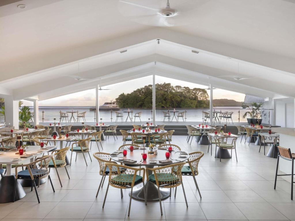a room with tables and chairs and a view of the water at Novotel Suva Lami Bay in Suva