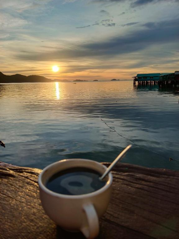 a cup of coffee sitting on a table next to the water at Chill House kohchang in Ban Bang Bao
