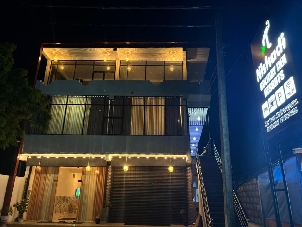 a building with a sign in front of it at night at Nishadi Holiday Inn Kataragama in Kataragama