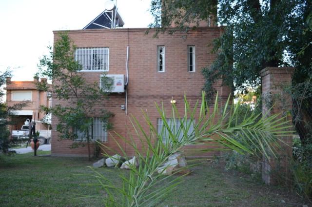 una casa de ladrillo con una planta delante en Departamentos Riosierras en Alta Gracia