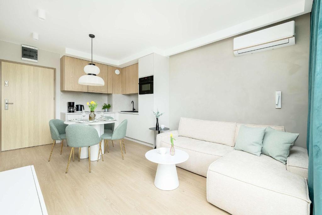 ein Wohnzimmer mit einer weißen Couch und einem Tisch in der Unterkunft Stylish Apartment in Kołobrzeg with Air Conditioning and Parking by Noclegi Renters in Luboszyce