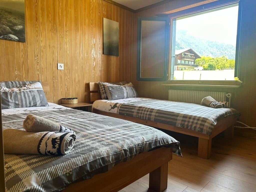 Dos camas en una habitación con ventana. en Chalet Zytrösli, en Sigriswil