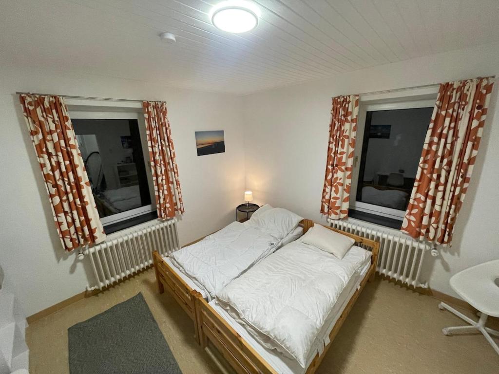 a small bedroom with a bed and two windows at Ecolodge 1 Mini Apartment in Niederdorla
