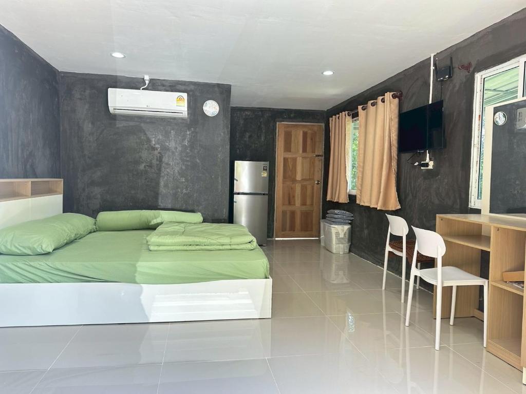 a bedroom with a green bed and a kitchen at Villa Krabi Center in Ban Nong Chaeng