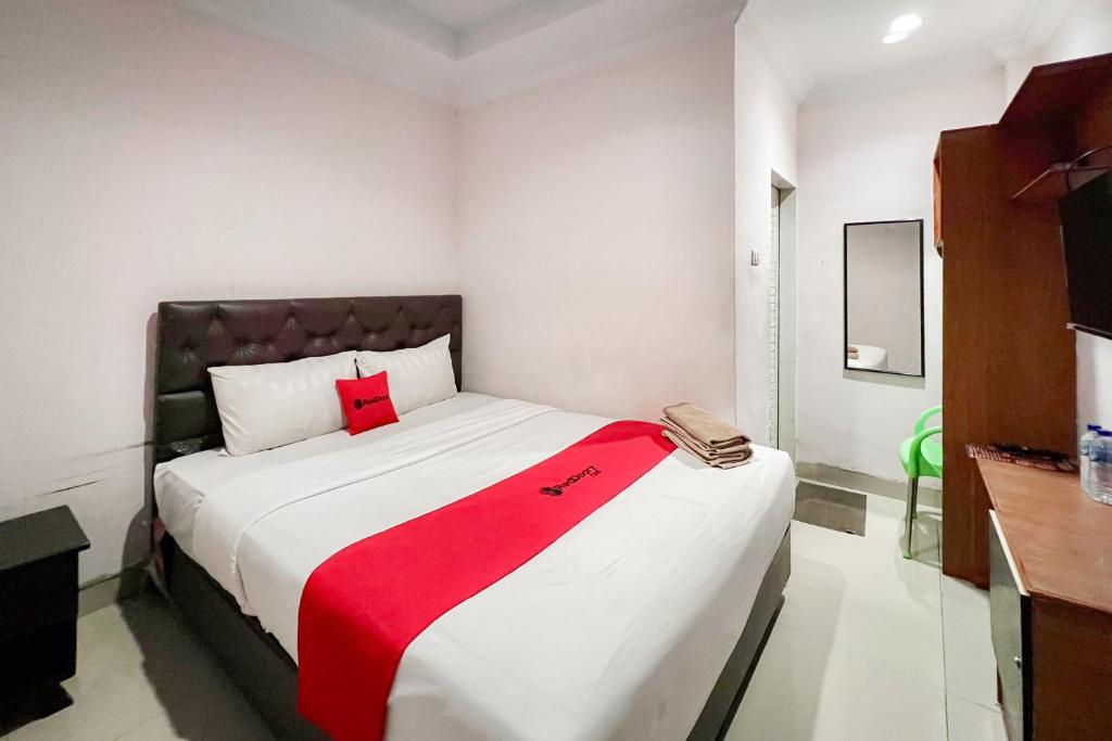 a bedroom with a large bed with a red blanket on it at RedDoorz at Vania Residence Medan in Medan