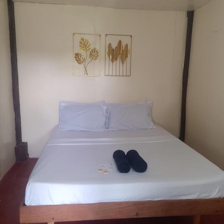 ein Bett mit zwei Paar Schuhen darauf in der Unterkunft Kubo ni klay in San Isidro