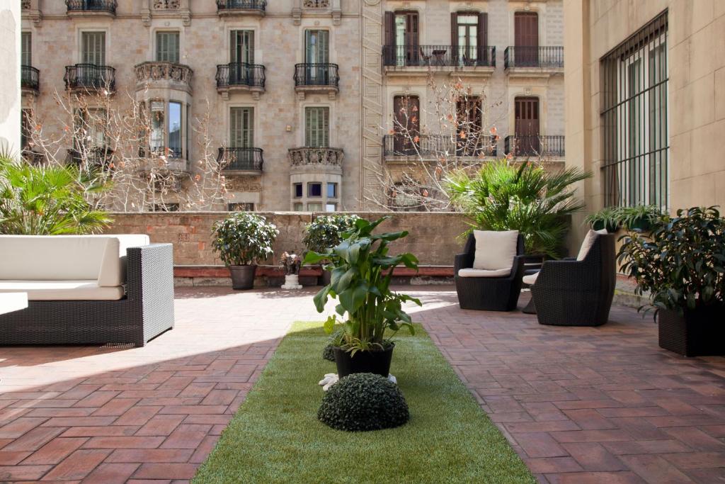 dziedziniec z krzesłami i roślinami przed budynkiem w obiekcie Hostal Boutique Khronos w Barcelonie