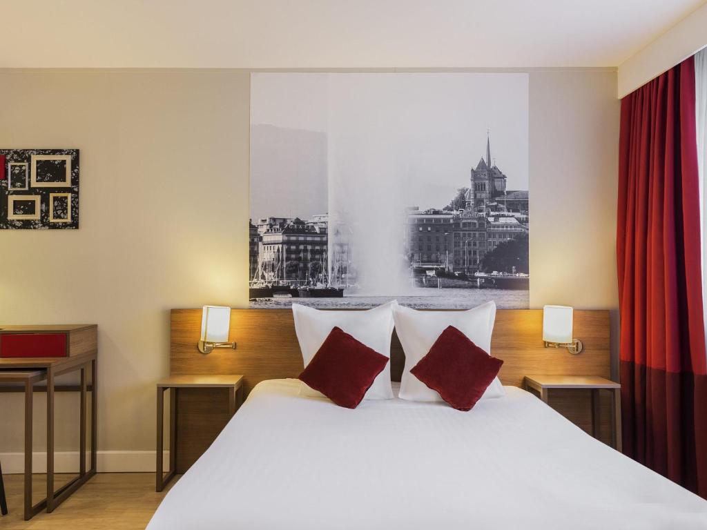 a bedroom with a large white bed with red pillows at Adagio Original Thoiry Genève in Thoiry